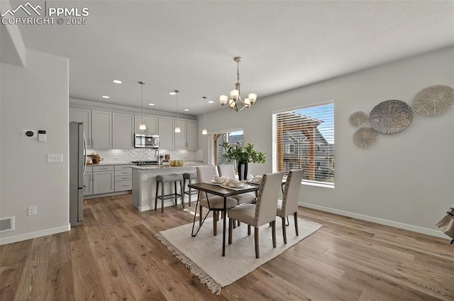 dining room featuring a chandelier, recessed lighting, light wood finished floors, and baseboards