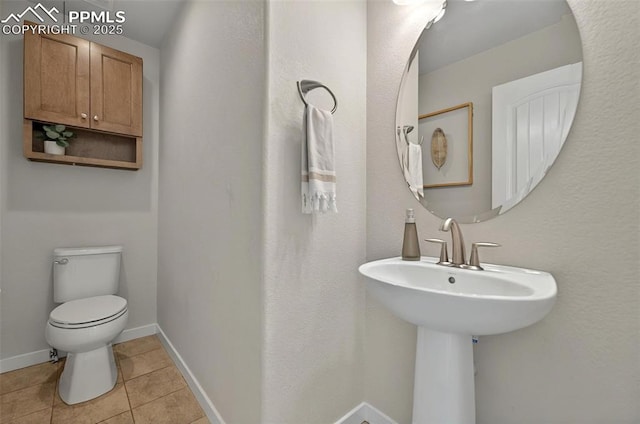 half bath with tile patterned floors, toilet, and baseboards