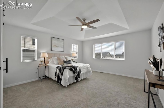 carpeted bedroom featuring a raised ceiling, baseboards, and ceiling fan
