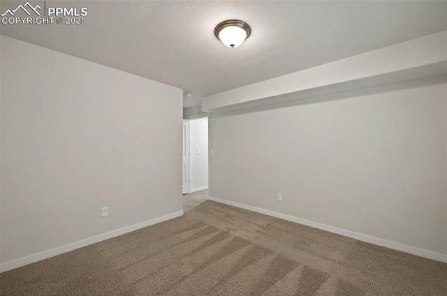 empty room featuring carpet and baseboards