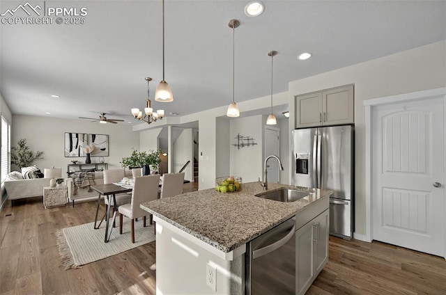 kitchen with appliances with stainless steel finishes, a sink, a ceiling fan, light stone counters, and hanging light fixtures