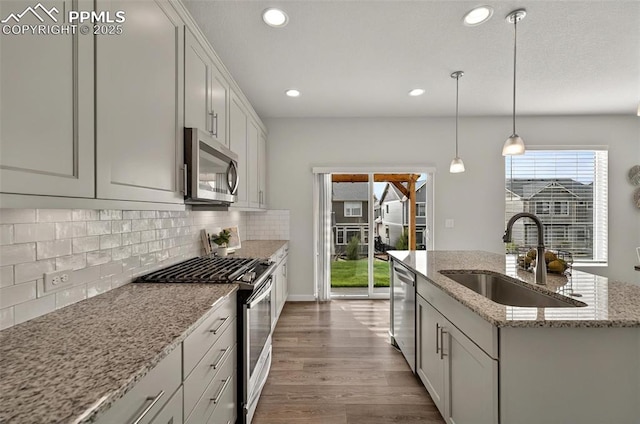 kitchen featuring appliances with stainless steel finishes, a sink, recessed lighting, backsplash, and dark wood-style flooring
