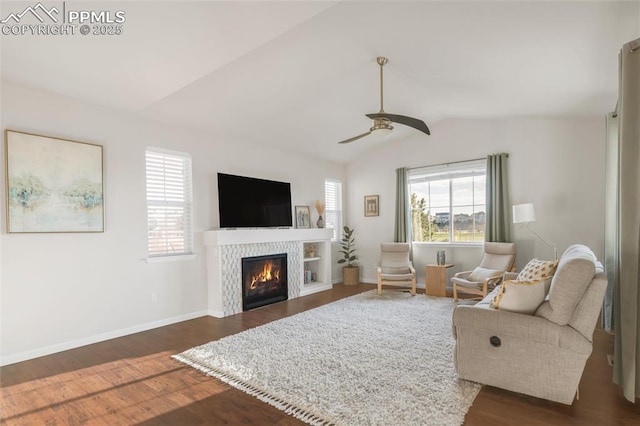 living room featuring healthy amount of natural light, lofted ceiling, ceiling fan, dark wood-type flooring, and baseboards
