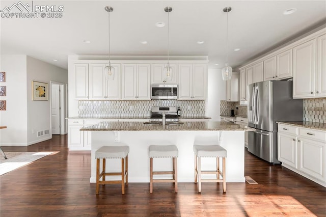 kitchen featuring stainless steel appliances, a sink, decorative backsplash, a breakfast bar, and light stone countertops