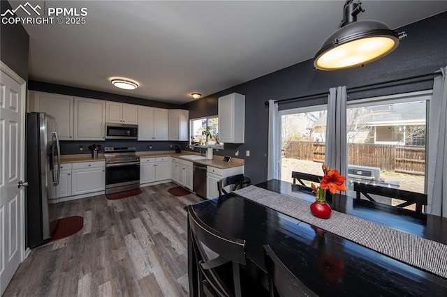 7511 Coffee Rd, Peyton, CO 80831 - kitchen featuring appliances with stainless steel finishes, a sink, wood finished floors, white cabinetry, and light countertops