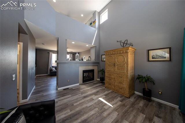 7511 Coffee Rd, Peyton, CO 80831 - living room featuring wood finished floors, baseboards, a towering ceiling, recessed lighting, and a fireplace