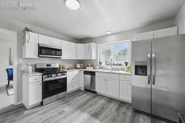 308 Steven Dr, Colorado Springs, CO 80911 - kitchen with stainless steel appliances, a sink, white cabinets, and light wood finished floors