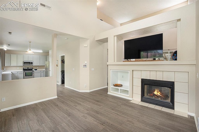 7120 Bonnie Brae Ln, Colorado Springs, CO 80922 - unfurnished living room featuring wood finished floors, a sink, baseboards, and a tile fireplace