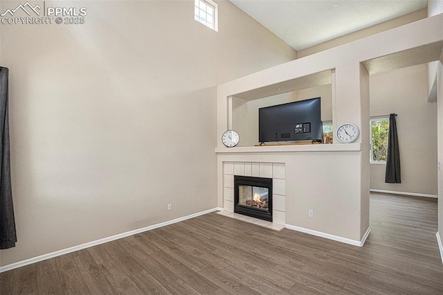 7120 Bonnie Brae Ln, Colorado Springs, CO 80922 - unfurnished living room featuring wood finished floors, baseboards, a fireplace, and a towering ceiling
