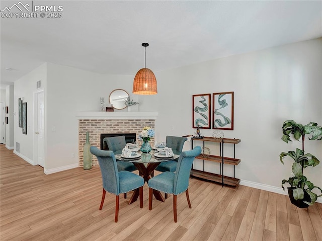 2209 Gilpin Ave, Colorado Springs, CO 80910 - dining area with light wood-style flooring, baseboards, and a brick fireplace