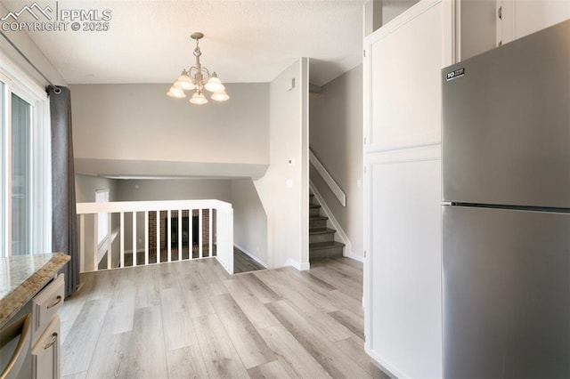 8230 Contrails Dr, Colorado Springs, CO 80920 - interior space featuring a chandelier, light wood-style flooring, baseboards, and stairs