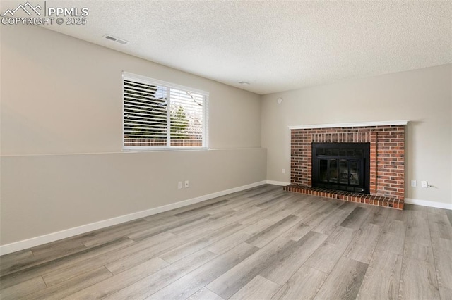 8230 Contrails Dr, Colorado Springs, CO 80920 - unfurnished living room with wood finished floors, a textured ceiling, a brick fireplace, and baseboards