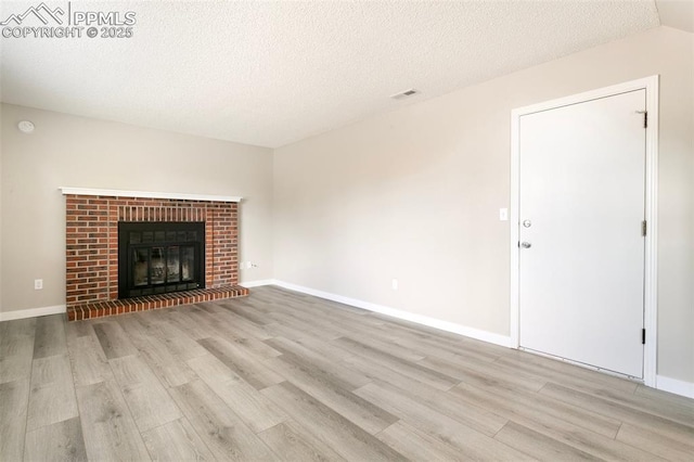 8230 Contrails Dr, Colorado Springs, CO 80920 - unfurnished living room featuring light wood-style flooring, a textured ceiling, a fireplace, and baseboards