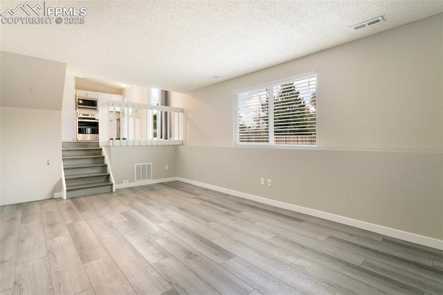 8230 Contrails Dr, Colorado Springs, CO 80920 - spare room featuring wood finished floors, a textured ceiling, stairway, and baseboards