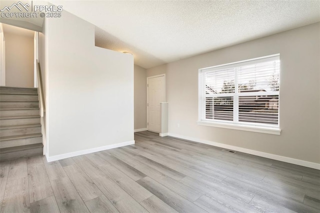 8230 Contrails Dr, Colorado Springs, CO 80920 - unfurnished living room with wood finished floors, baseboards, a textured ceiling, and stairway