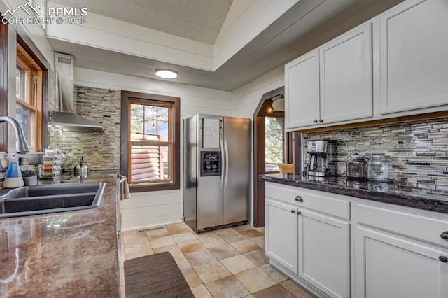 kitchen featuring stainless steel fridge, a sink, wall chimney exhaust hood, and backsplash