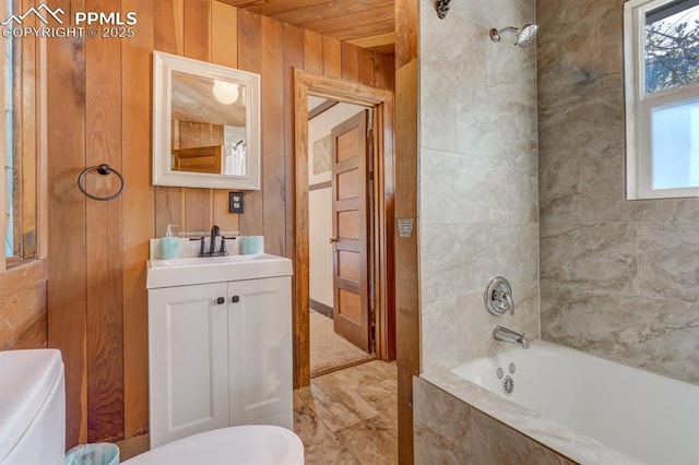 bathroom featuring toilet, wood walls, healthy amount of natural light, vanity, and shower / bathtub combination
