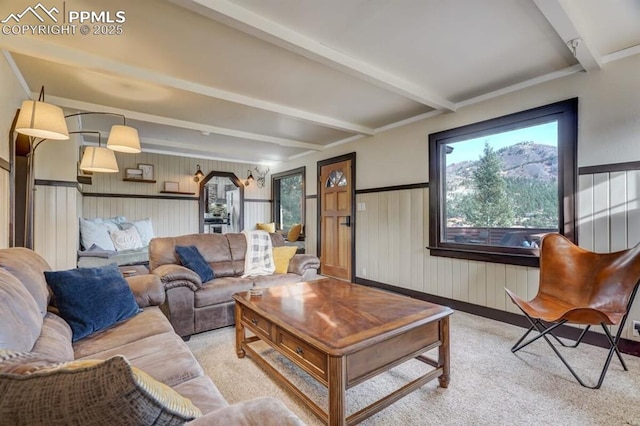 living area with healthy amount of natural light, beam ceiling, light carpet, wooden walls, and wainscoting