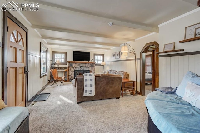 living room featuring carpet, beam ceiling, a fireplace, and a wainscoted wall