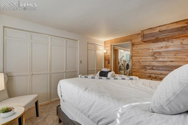 bedroom featuring carpet flooring, separate washer and dryer, multiple closets, and wooden walls