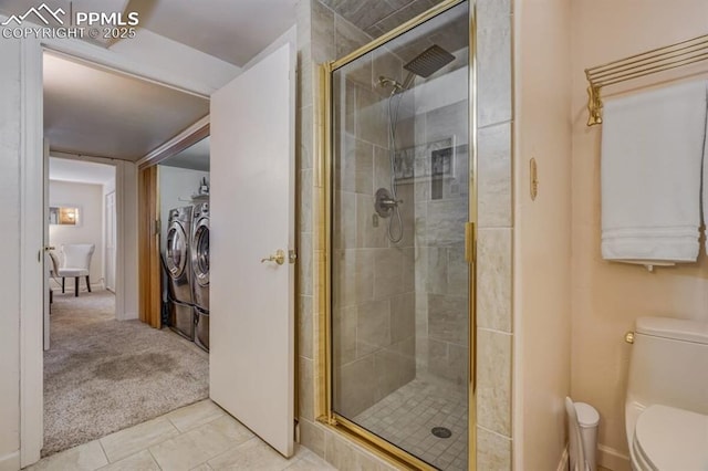 full bath with a shower stall, toilet, washer and dryer, and tile patterned flooring
