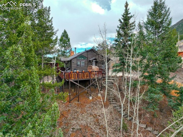 back of house featuring a deck, log siding, and a chimney