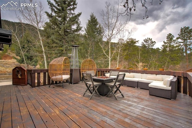 wooden terrace with an outdoor living space with a fire pit