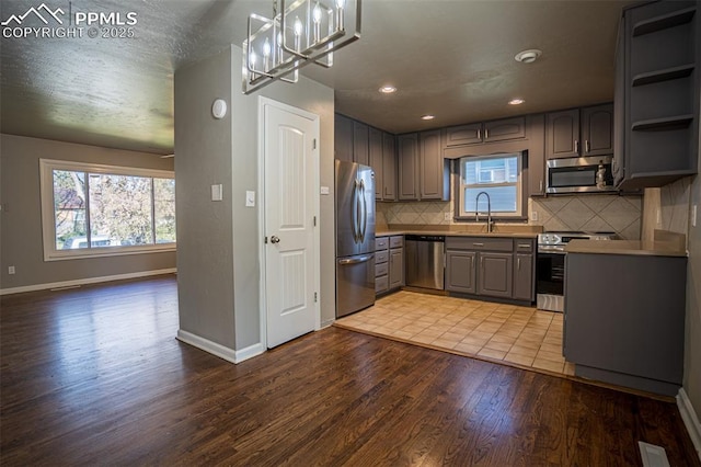 1701 Grant Ave, Colorado Springs, CO 80909 - kitchen with stainless steel appliances, gray cabinetry, light wood-type flooring, a sink, and baseboards