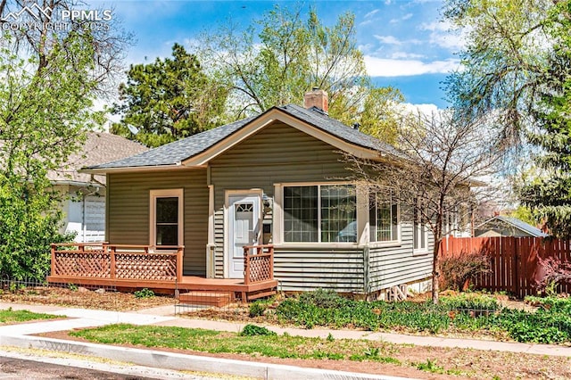 427 N Walnut St, Colorado Springs, CO 80907 - bungalow with a shingled roof, fence, a wooden deck, and a chimney