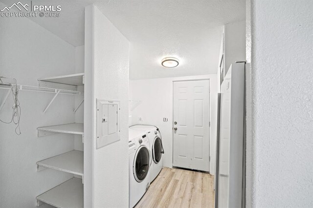 9775 Indian Village Hts, Fountain, CO 80817 - laundry area with washing machine and dryer, light wood-type flooring, electric panel, and a textured ceiling