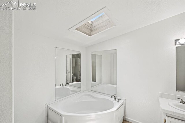 9775 Indian Village Hts, Fountain, CO 80817 - bathroom featuring a skylight, toilet, a garden tub, vanity, and lofted ceiling