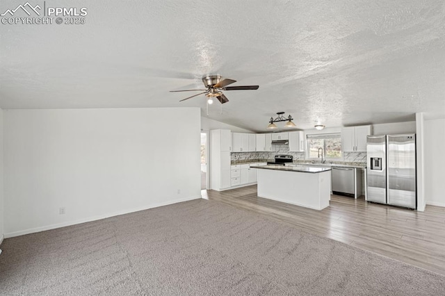 9775 Indian Village Hts, Fountain, CO 80817 - kitchen featuring appliances with stainless steel finishes, open floor plan, light carpet, a textured ceiling, and vaulted ceiling