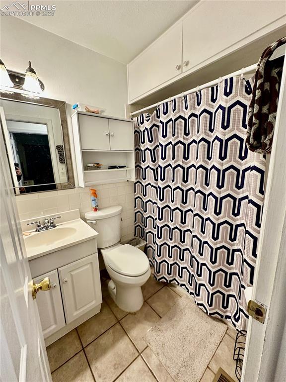 1701 Jerry Murphy Rd, Pueblo, CO 81001 - full bath with tile walls, tile patterned floors, vanity, toilet, and a shower with shower curtain
