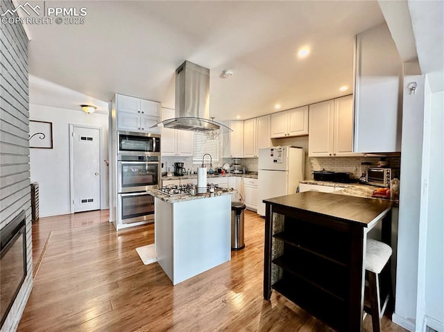 1701 Jerry Murphy Rd, Pueblo, CO 81001 - kitchen with island exhaust hood, stainless steel appliances, backsplash, white cabinetry, and recessed lighting