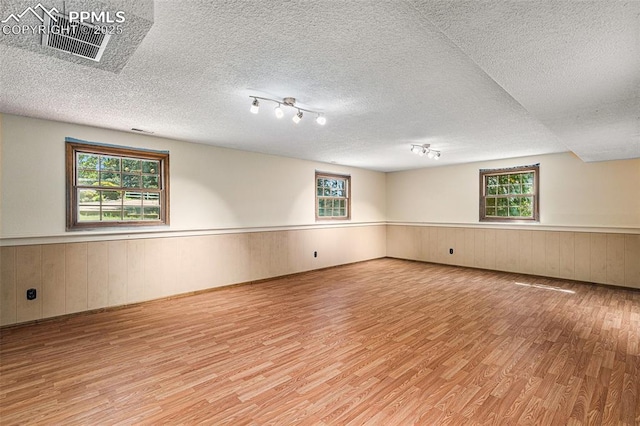 7210 Antelope Ln, Colorado Springs, CO 80920 - empty room with light wood finished floors, wainscoting, healthy amount of natural light, a textured ceiling, and wood walls