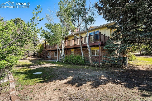 7210 Antelope Ln, Colorado Springs, CO 80920 - back of house featuring stairway, brick siding, a deck, and a lawn