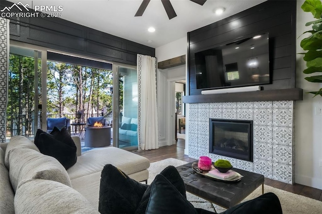 living area featuring a ceiling fan, wood finished floors, a tile fireplace, and recessed lighting