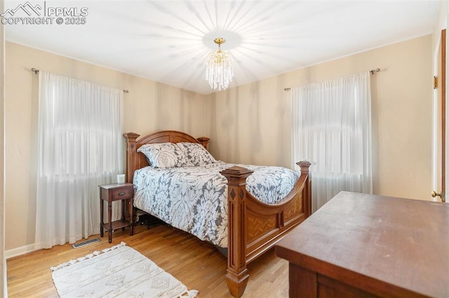 bedroom with a chandelier and light wood-type flooring