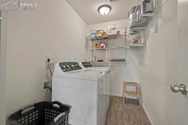 clothes washing area with independent washer and dryer, wood finished floors, and baseboards