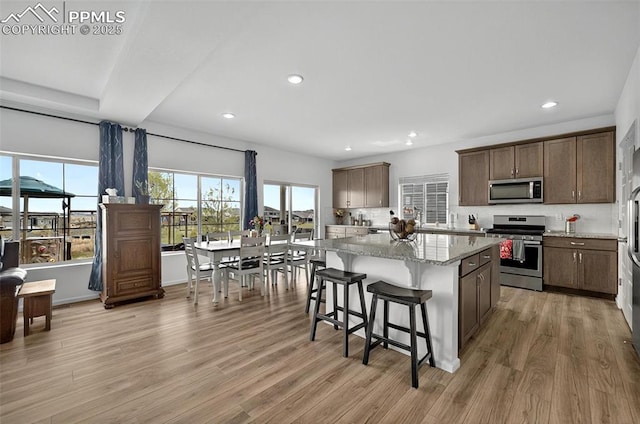 kitchen with stainless steel appliances, recessed lighting, a kitchen breakfast bar, a kitchen island, and light wood-style flooring
