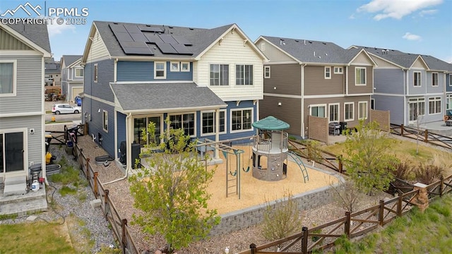 back of property with solar panels, a shingled roof, a residential view, a fenced backyard, and a patio