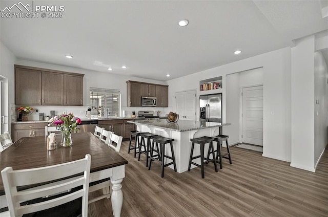 kitchen featuring stainless steel appliances, wood finished floors, a kitchen island, a sink, and recessed lighting