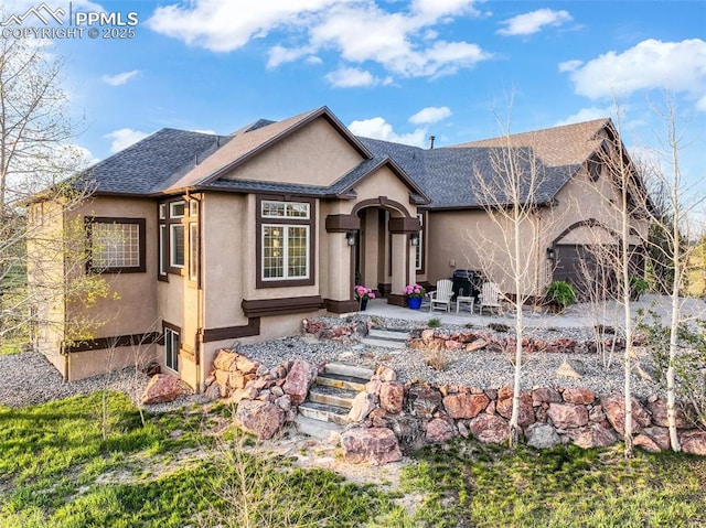 view of front of home featuring stucco siding, a shingled roof, and a patio area