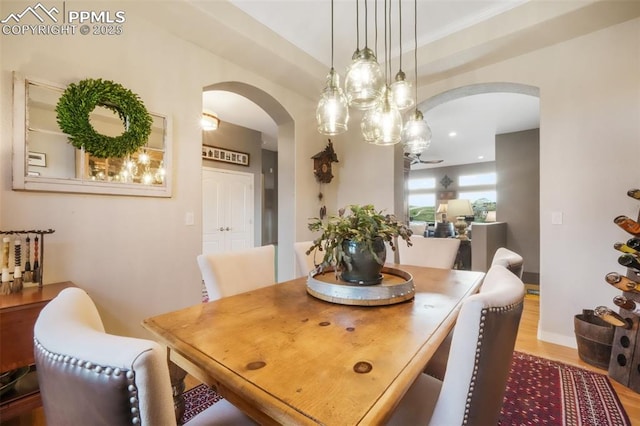 dining space featuring arched walkways and wood finished floors