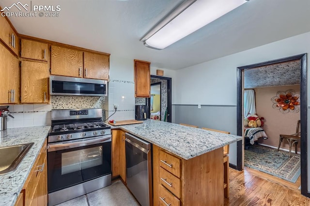 319 S Institute St, Colorado Springs, CO 80903 - kitchen with appliances with stainless steel finishes, a peninsula, brown cabinetry, and decorative backsplash