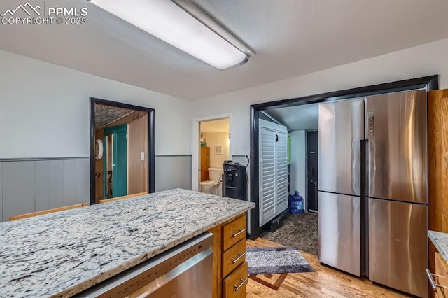 319 S Institute St, Colorado Springs, CO 80903 - kitchen featuring appliances with stainless steel finishes, brown cabinetry, light wood finished floors, and light stone countertops