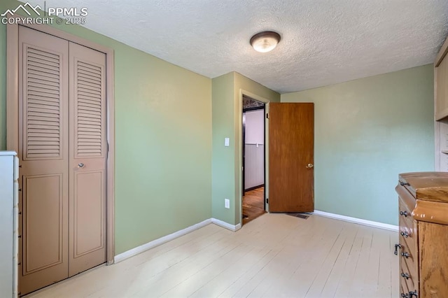 319 S Institute St, Colorado Springs, CO 80903 - unfurnished bedroom with light wood finished floors, a textured ceiling, baseboards, and a closet