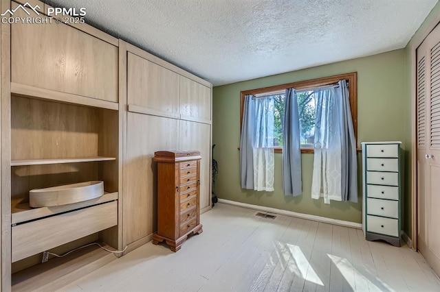319 S Institute St, Colorado Springs, CO 80903 - unfurnished bedroom with light wood-style floors, a textured ceiling, baseboards, and a closet