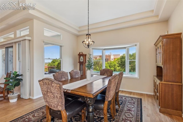 2744 La Strada Grande Hts, Colorado Springs, CO 80906 - dining space with a chandelier, light wood finished floors, a tray ceiling, and baseboards