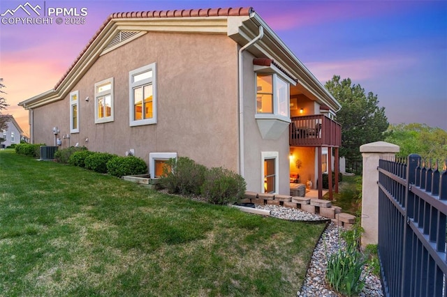2744 La Strada Grande Hts, Colorado Springs, CO 80906 - back of property at dusk with a balcony, stucco siding, and central air condition unit
